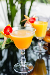 bright glasses with cold alcoholic cocktail with orange juice on a wooden table in a restaurant with creative decoration of berries, fresh mint and orange slices. soft focus