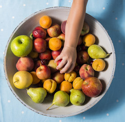 taking a fruit from a bowl, blue background