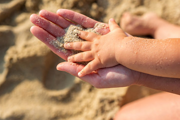 Mother and child's hands on the beach