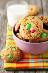 Cookies with colorful candy in bowl on grey wooden background