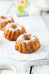 Bundt cakes on cutting board on white wooden background