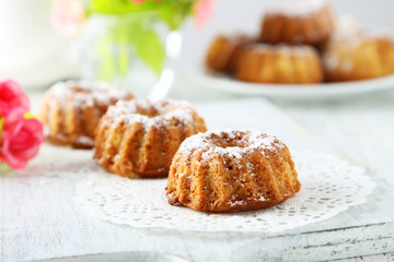 Bundt cakes on cutting board on white wooden background