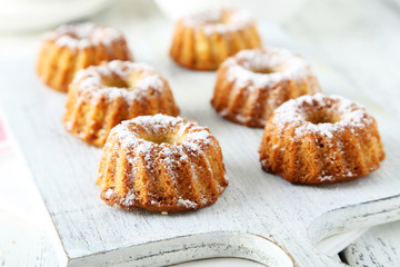 Bundt cakes on cutting board on white wooden background