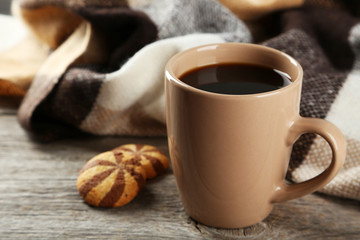 Cup of coffee with plaid on grey wooden background