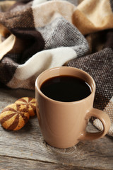 Cup of coffee with plaid on grey wooden background