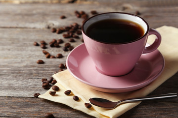 Cup of coffee with coffee beans on grey wooden background