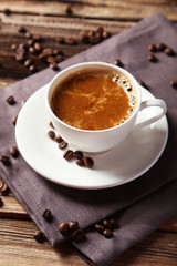Cup of coffee with coffee beans on brown wooden background