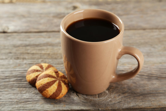 Cup of coffee with cookies on grey wooden background