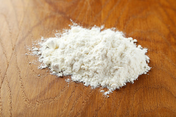 Heap of wheat flour on brown wooden background