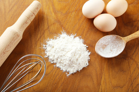 Heap of wheat flour with eggs, rolling pin and spikelets on brow