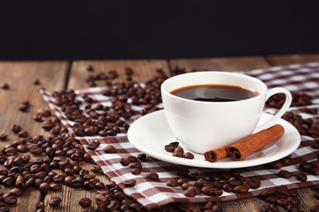 Cup of coffee with cinnamon on brown wooden background