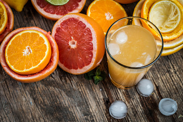 Juice glass and fresh citrus fruit on rustic wood