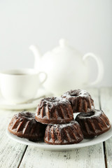 Chocolate bundt cakes on plate on white wooden background