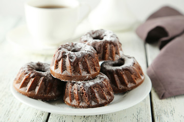 Chocolate bundt cakes on plate on white wooden background
