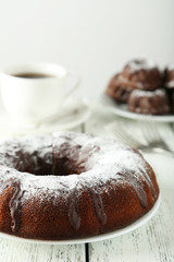 Chocolate bundt cake on plate on white wooden background