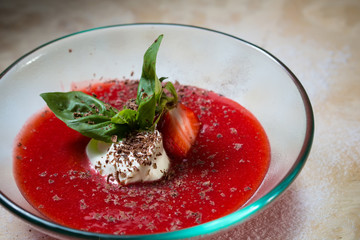 strawberry soup with ice cream and mint on a plate