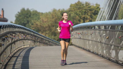 Young girl Jogging via a pedestrian bridge in the city.