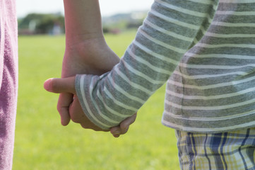 Hand of siblings holding hands in the park