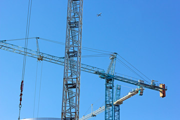 Three construction cranes work a side by side. 