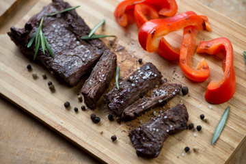 Sliced well-done grilled beef steak machete on a chopping board