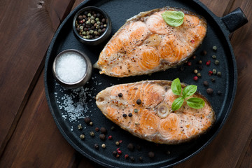 Frying pan with two roasted salmon steaks, view from above