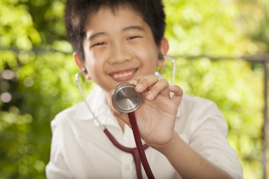 Asian young boy having stethoscope playing doctor