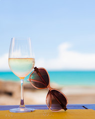 glass of chilled white wine and sunglasses on table near the
