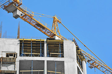 Crane and building construction site against blue sky
