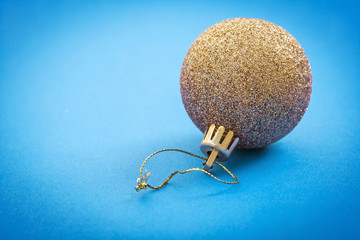 gold colored christmas bauble on light blue background