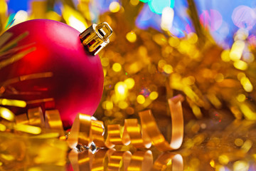 red christmas bauble on background of blurred tinsel