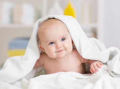 smiling baby girl lying under towel