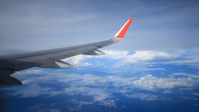 View of airplane wing flying above clouds in sky