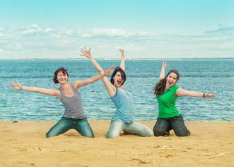 Three happy women sitting on the beach