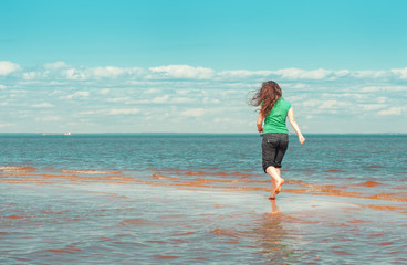 Fototapeta na wymiar Happy woman running on the water of sea