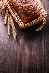 Bread with seeds in wicker basket wheat ears on vintage pine boa