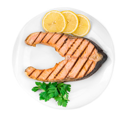 Grilled salmon steak with vegetables on plate.