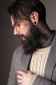 young man with a long beard and tatoos posing in the studio