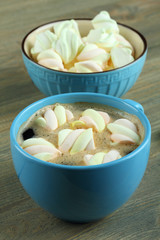 A cup of hot chocolate with marshmallows on the wooden background