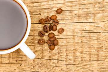 Cup of black coffee and coffee beans on old wooden table
