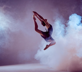 Beautiful young ballet dancer jumping on a lilac background.  - obrazy, fototapety, plakaty
