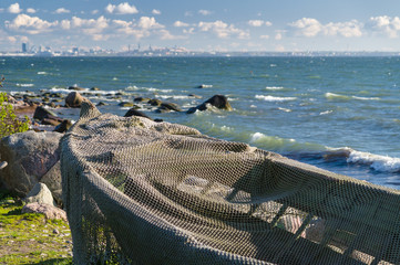 Boat covered by fisherman net at seashore and modern cityscape