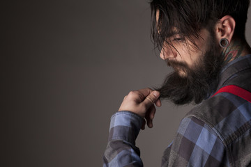 a young man with a beard and mustache touching his beard