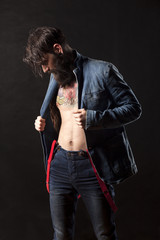 a young man with a beard wearing a denim jacket and jeans