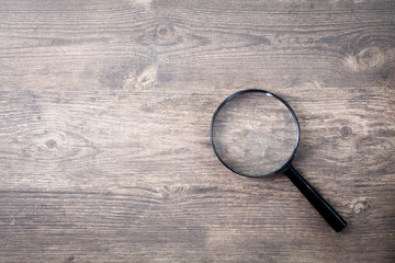 Magnifying glass on wooden table, Search and discover symbol