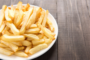 French fries on white dish on wooden background