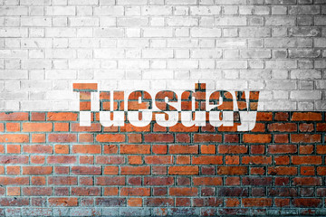 Fototapeta na wymiar Red Brick wall texture with a word Tuesday