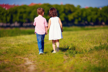 two cute kids walking away on summer field