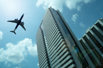 Naklejka premium Airplane in the sky with modern buildings