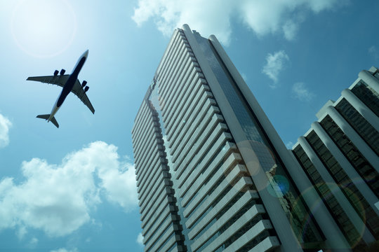 Airplane in the sky with modern buildings
