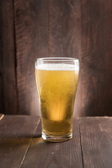 Glass of light beer on wooden background.